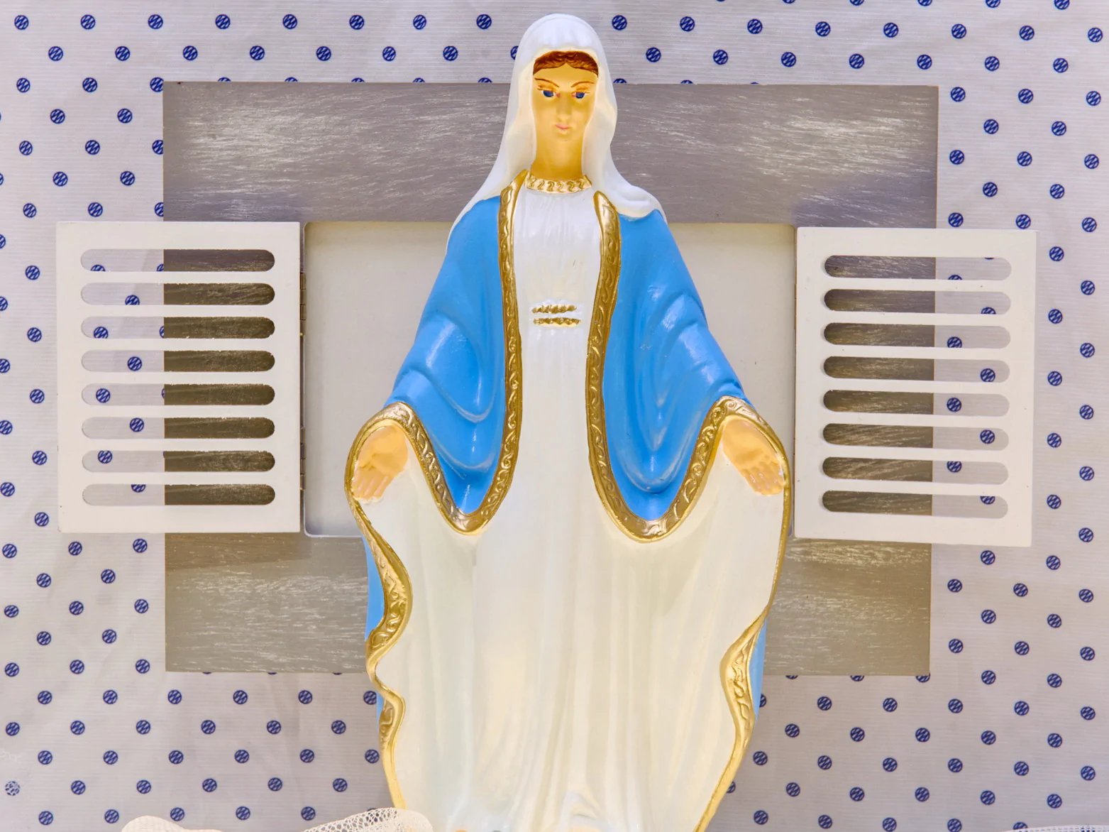 Figura Matki Boskiej w niebieskim płaszczu ze złotymi zdobieniami i pudełkami porcji paliuszków