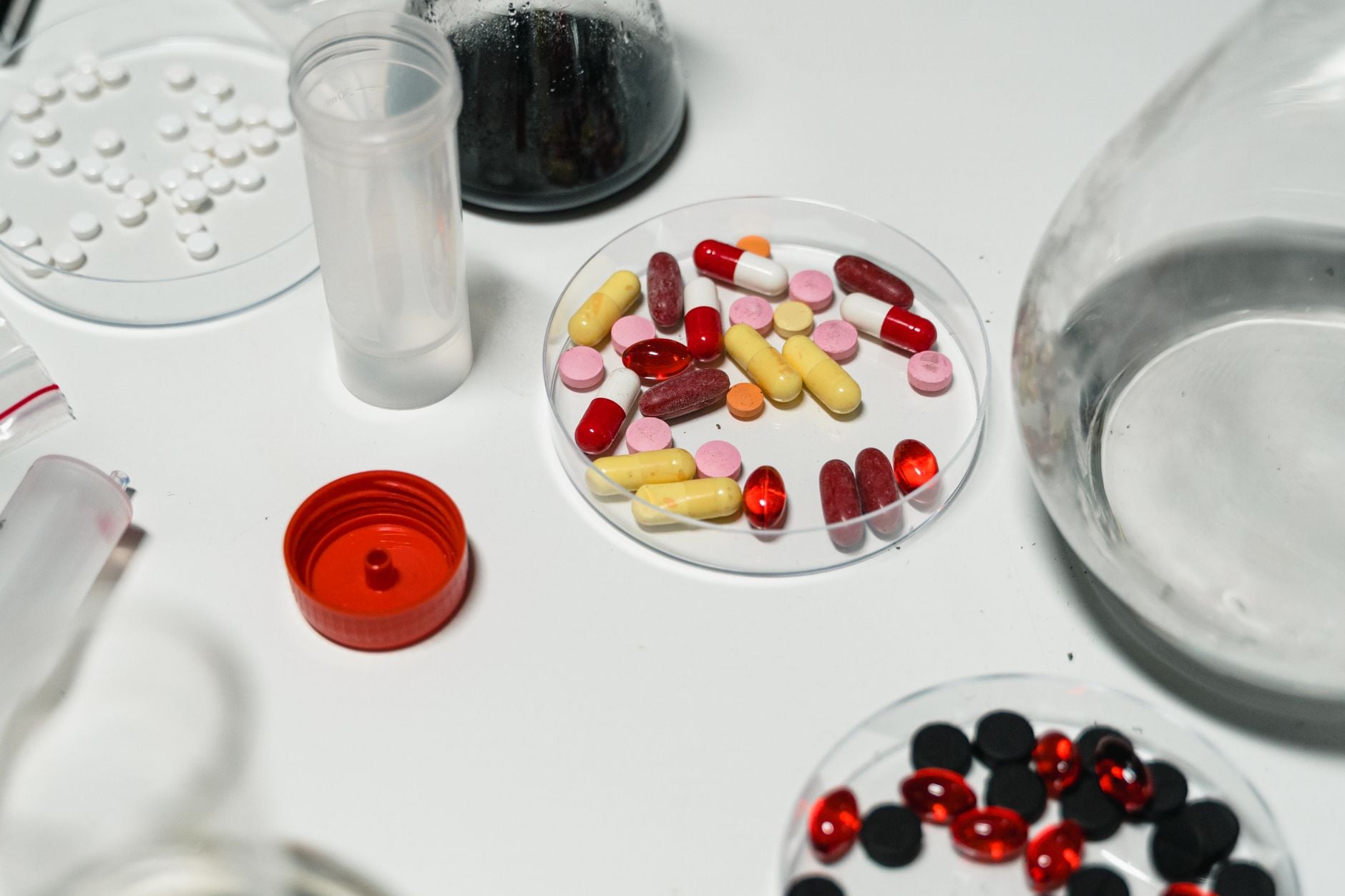 Różnokolorowe kapsułki i tabletki w szalkach Petriego w laboratorium farmaceutycznym